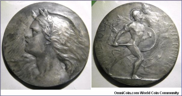 1900 France Musique Guerriere Medal distributed to members of the Society Friends of French by Paul Francois Niclausse. Silver: 60MM./3.6 oz.
Obv: Female bust, lauerate haed left, before a harp signed P. Niclausse. Rev: MUSIC WARRIOR. Ancient warrior naked, helmeted and armed with a sword & shield right before an allegory equipped with a harp signed P. Nivlausse.
