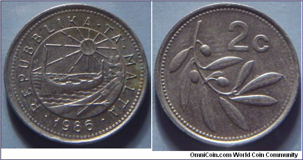 Malta | 
2 Cents, 1986 | 
17.78 mm, 2.26 gr. | 
Copper-nickel | 

Obverse: Coastal scene with the rising sun, a traditional Maltese boat (Luzzu), a shovel and a pitchfork, an Opuntia plant, date below | 
Lettering: • REPUBBLIKA • TA' • MALTA • 1986 | 

Obverse: Olive bransch, denomination right | 
Lettering: 2c |