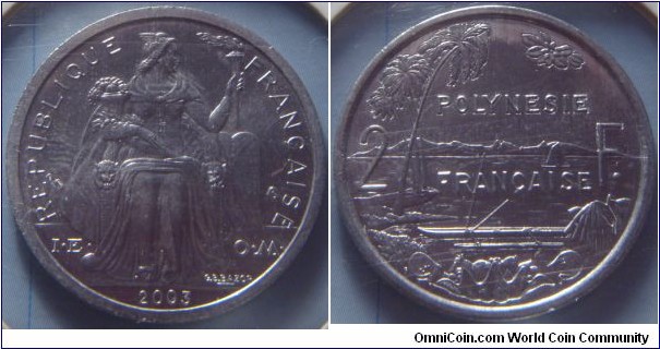 French Polynesia | 
2 Francs, 2003| 
27 mm, 2.2 gr. | 
Aluminium | 

Obverse: Seated Liberty on throne holding lit torch and assorted fruit facing right, date below | 
Lettering: REPUBLIQUE FRANÇAISE I•E • O•M• 2003 | 

Reverse: Palm trees on left, sailboat at sea min centre, mountains in distance. Boat with outrigger in foreground with assorted fruit in container, divide denomination| 
Lettering: POLYNESIE FRANÇAISE 2 F. |