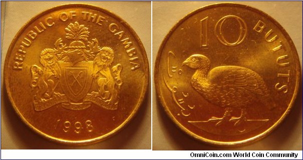 The Gambia | 
10 Bututs, 1998 | 
26 mm, 5.6 gr. | 
Brass plated Steel | 

Obverse: National Coat of Arms, date below | 
Lettering: REPUBLIC OF THE GAMBIA 1998 | 

Reverse: Double-spurred francolin | 
Lettering: بتوت 10 BUTUTS |