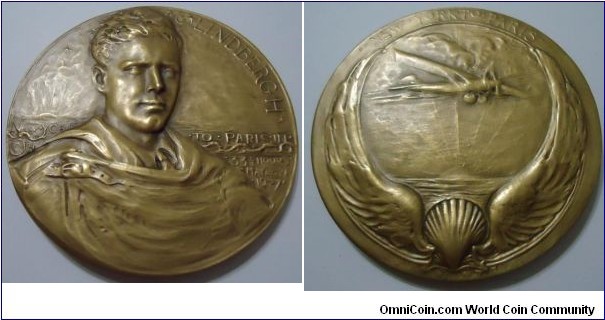 1927 USA Charles A. Lindbergh Lone Eagle Medal strunk by Medallic Art Co., engraved by Charles Hinton. Gold plated Bronze: 69.7MM.
Obv: Inscribed: C LINDBERGH to the right of a bust of Lindbergh wrapped in a rope and NEW YORK on the left of the bust and TO PARIS IN 33 1/3 HOURS MAY 20 21/1927 on the right. Signed to the left of the bust with sculptor's monogram.@H. Rev: Inscribed above NEW YORK TO PARIS, a depiction of the Spirit of St. Louis with a boarder of wings and a shell below centre, symbolizing flying and ocean. The sun setting in the background denoted the passing of a day, during which the Lone Eagle winged his way to France. Below the shell is inscribed 1927. Edge: Inscribed MEDALLIC ART CO LTD.
