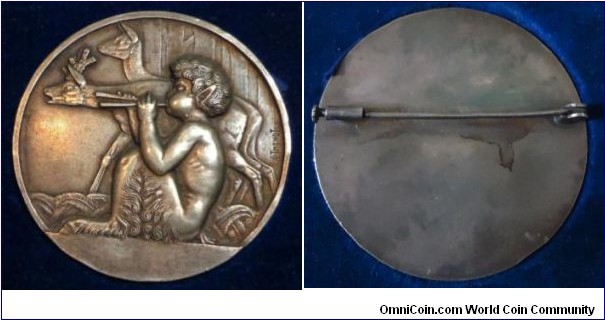 1900 o.j. France Jeune Enfant, Jouant De La Flute uniface Medal by Thenot. Plated Bronze: 50MM./37 gms.
Image of Faune playing flute & with two antelope, signed THENOT on right. The faun is a half human - half goat (from the head to the waist being the human half, but with the additional of golt's horns., manifestation of forest and animal spirits which would help or hinder humans at whim. Romans believed fauns inspired fear in men traveling in lonely, remote or wild places but were also capable of guiding humans in need. The reverse is blank.
