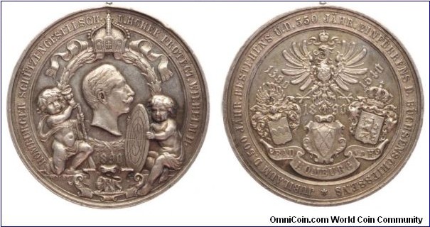1890 German 350th Anniversary of The Shooting Association Medal by Wilhelm & Mayer. Silver: 39.32MM./21.77 gms.
Obv: Half-length portrait of Wilhelm II to right, next to two putti with gun & target disc. Rev: 3 Costed of Arms and The Imperial Eagle above.
