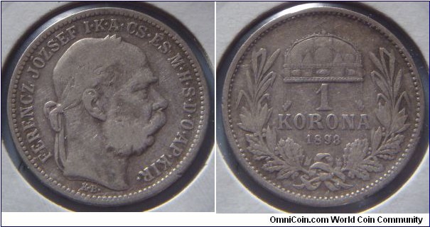 Kingdom of Hungary | 
1 Korona, 1893 | 
23 mm, 5 gr. | 
Silver (.835) | 

Obverse: Emperor Franz Joseph I (I. Ferencz József) facing right | 
Lettering: FERENC JÓZSEF I•K•A•CS•ÉS M•H•S•D•O•AP•KIR• | 

Reverse: Wreath with crown with crooked cross, denomination below, date bottom | 
Lettering: 1 KORONA 1893 |