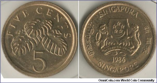 Singapore 1986 5 cents. Metal: Aluminium Bronze, 1.56g, 16.75mm. Featuring the Arms of Republic of Singapore with the year 1986 with 4 official languages around the circumference of the coins. It also features a fruit salad plant or goes by the scientific name, Monstera deliciosa.