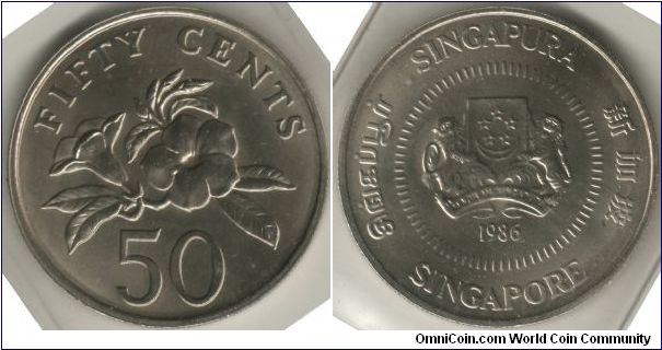 Singapore 1986 50 cents. Metal: Cupro-Nickel, 7.29g, 24.66mm. Featuring the Arms of Republic of Singapore with the year 1986 with 4 official languages around the circumference of the coins with additional ring of dashes around the arms. It also features yellow allamanda (a poisonious plant which is quite common in Singapore) or better known as Allamanda cathartica.