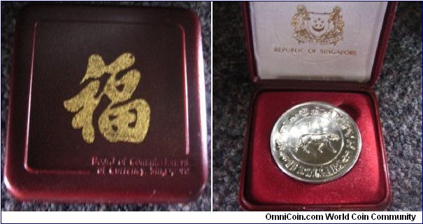 Box of Singapore 1986 10 dollar tiger coin. The calligraphy on the box means good luck in Chinese.