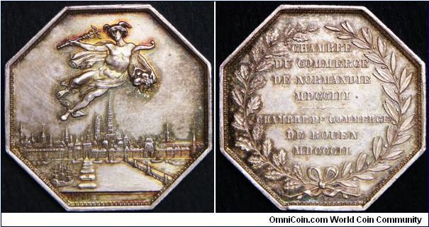 Silver jeton issued by the Chambre de Commerce de Rouen, 1802. Obv. Mercury holding a caduceus and a horn of flying abundance above the city and harbor of Rouen; signature to epigraph LECOMTE F.. 1880s restruck's jeton. Nice toned.