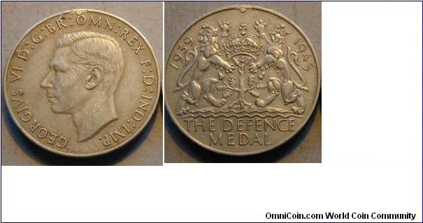 1939-1945 Britian Defence Medal for service on shore for 3 years. 36MM
Obv: Depicts head of King George VI with legend GEORGIVS VI D; G;BR.OMN;REX.F:D:IND:IMP. Rev: Britian Arm of coat 1939-1945 THE DEFENCE MEDAL.
